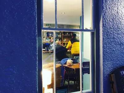 a reflection of a group of people in a window at The Cornubia Inn in Hayle