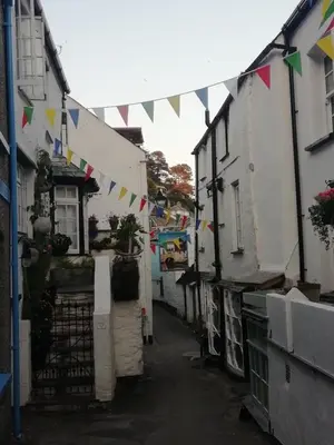 a narrow alley with flags hanging from buildings at The House on the Props in Polperro