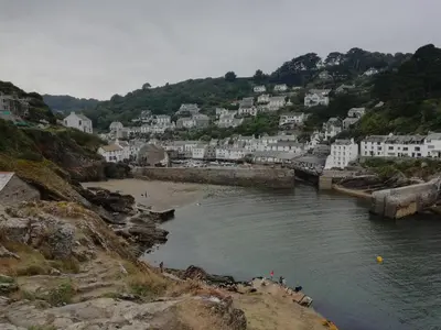 a group of people standing on a beach next to a river at The House on the Props in Polperro