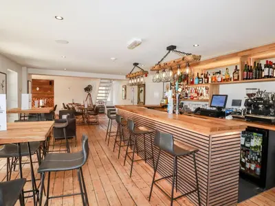 a bar in a restaurant with tables and chairs at 4 Water's Edge in Looe