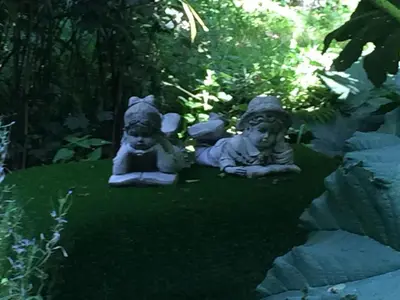 two statues sitting on the grass in a garden at Millbrook in Helston