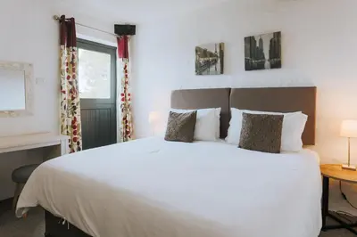 a bedroom with a large white bed and a window at Goonwinnow Farm Cottages in Newquay