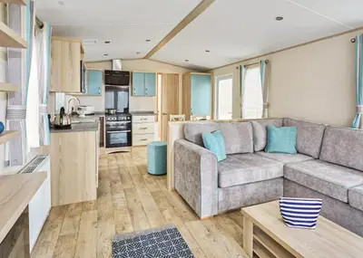 a living room with a couch and a kitchen at Trevornick Holiday Park in Holywell Bay