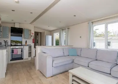 a living room with a couch and a kitchen at Trevornick Holiday Park in Holywell Bay