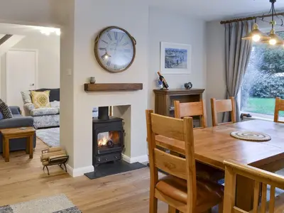 a dining room and living room with a wood stove at Treen in Lansallos