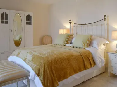a white bedroom with a bed with a gold blanket at Littlewood in Saint Columb Major