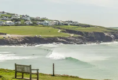 a bench sitting on a hill next to the ocean at 4 Pentire Rocks in Polzeath