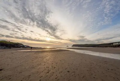 a person standing on a sandy beach with a cloudy sky at Webbs Retreat in Wadebridge