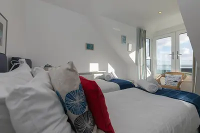 a bedroom with two beds and a window at Sea Crest in St Ives