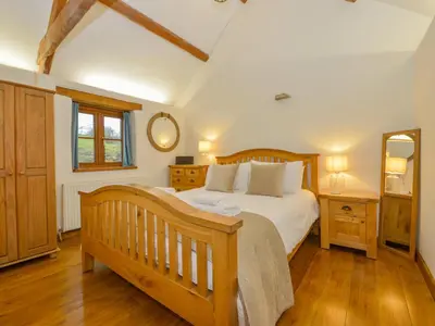 a bedroom with a wooden bed and a mirror at Hook Cottage in Looe