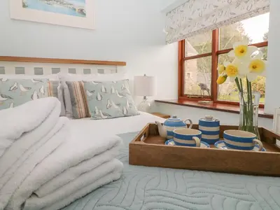 a bedroom with a bed with a tray of dishes at Erin Cottage in Pelynt