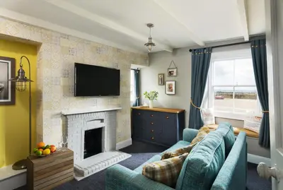a living room with a blue couch and a fireplace at Lifeboat Inn in St Ives