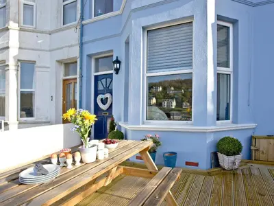 a deck with a wooden bench and a window at Kerensa in Looe