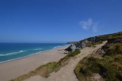 a sandy beach next to the ocean on a hill at Beach View Apartments in Porthtowan
