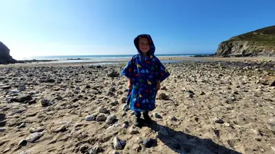 a young girl standing on a rocky beach at Beach View Apartments in Porthtowan