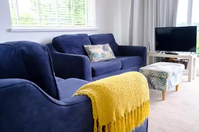 a living room with two blue couches and a tv at Cornish Coasts Holiday Park in Bude