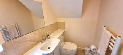 a bathroom with a sink and a toilet and a mirror at Sand Dunes in Perranporth
