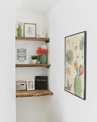a shelf with pictures and a picture frame on a wall at Poachers Pocket Cottage in Bodmin