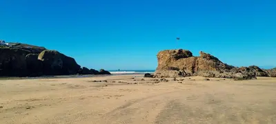 a beach with a rock with a flag on it at Warwick Lodge in Perranporth