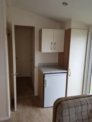 a small kitchen with a white refrigerator and cabinets at Caravan Willerby Rio in Looe
