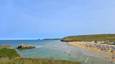 a group of people on a beach with the ocean at Chalet 151, Perran Sands in Perranporth