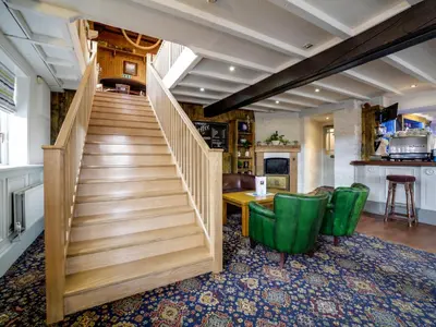 a staircase in a living room with green chairs at The Swan Hotel in Wadebridge