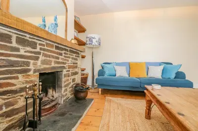 a living room with a blue couch and a fireplace at 1 Dormer Villas in Porthscatho