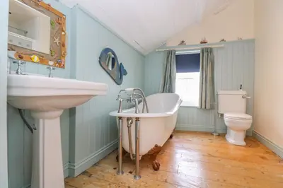a bathroom with a tub and a sink and a toilet at 1 Dormer Villas in Porthscatho