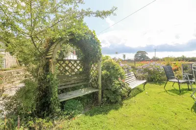 a wooden bench covered in ivy in a garden at Mill in Porthleven