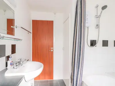 a bathroom with a sink and a wooden door at The Barn in Gunwalloe