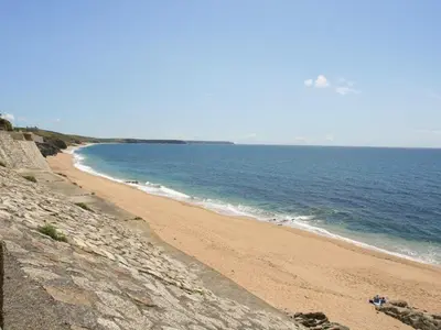 a sandy beach with the ocean in the background at Pegs in Porthleven