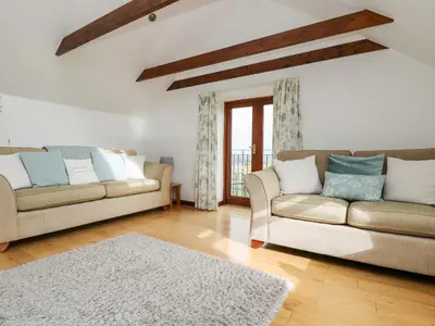 a living room with two couches and a rug at Castle Dore Barn in Par