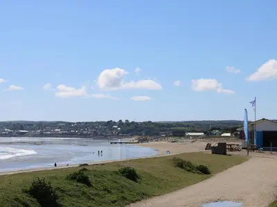 a beach with people on the sand and water at Surfside in Marazion