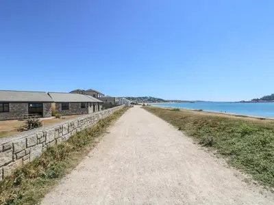 a dirt road next to a building and the water at Sea Shore in Marazion