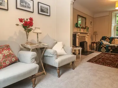 a living room with two chairs and a table with flowers at Banneth in Mawgan