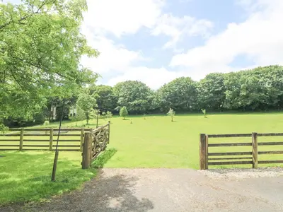 a fence in a field next to a field with trees at Byre in Lostwithiel