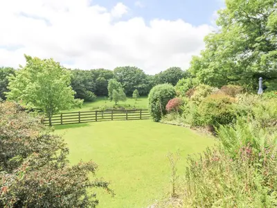 a large grassy yard with a wooden fence at Byre in Lostwithiel