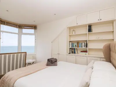 a bedroom with two beds and a book shelf at Porthmeor Beach House in St Ives