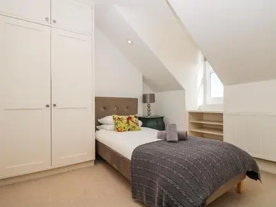 a white bedroom with a bed and a white cabinet at Porthmeor Beach House in St Ives