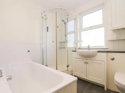 a white bathroom with a shower and a sink at Porthmeor Beach House in St Ives