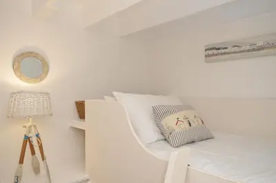 a white bedroom with a bed with a pillow on it at Stocks Barn in Liskeard
