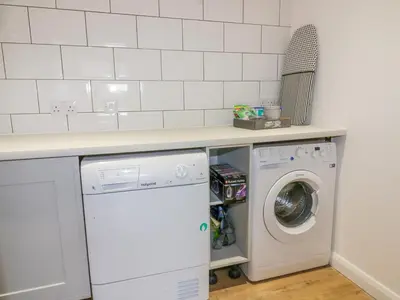 a kitchen with a washer and dryer under a counter at The Beach Halt in Perranporth