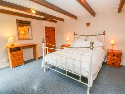 a bedroom with a bed and a desk and a mirror at Higher Lampra in Helston