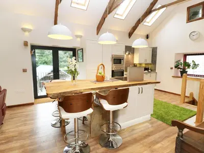 a kitchen with a large wooden table and bar stools at The Cart House in Liskeard