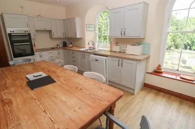 a kitchen with white cabinets and a wooden table at Beggars Roost in Truro