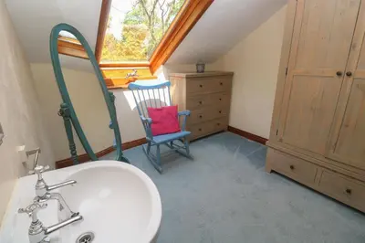 a bathroom with a sink and a chair and a window at Beggars Roost in Truro