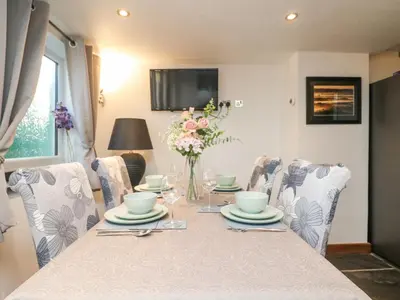 a dining room with a table with chairs and a television at Miner's Rest in Camborne