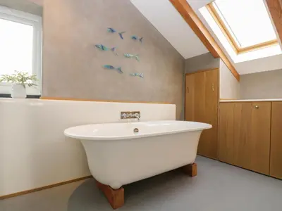 a white bath tub in a bathroom with birds on the wall at Miner's Rest in Camborne