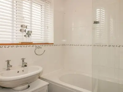 a white bathroom with a sink and a bath tub at Dune Haven in Truro