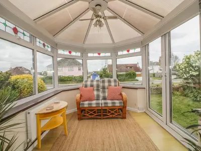 a screened in porch with a ceiling fan and a chair at Dune Haven in Truro